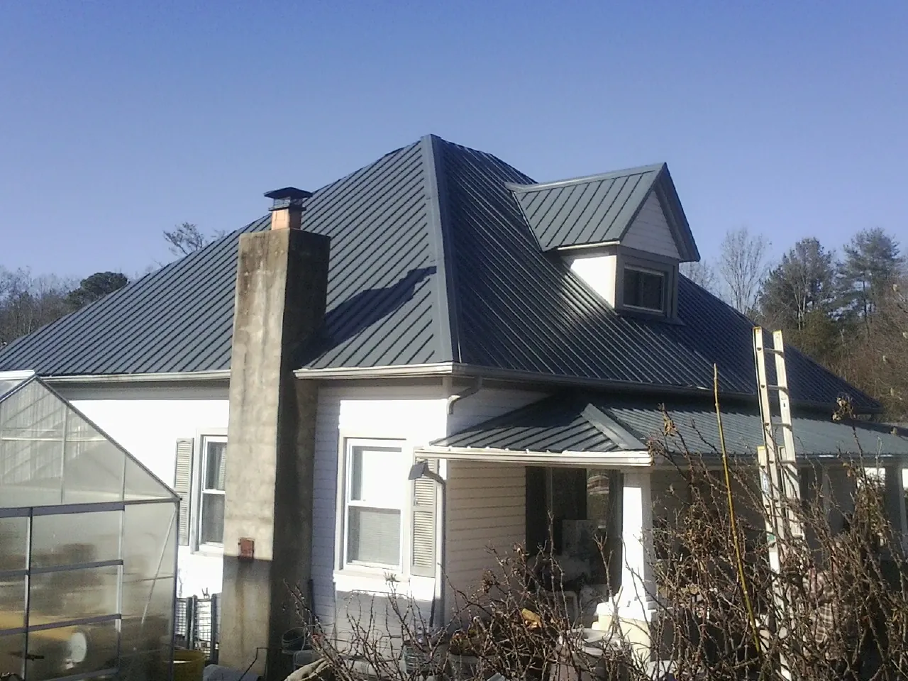 Dark blue standing seam metal roof on a white farmhouse with dormer — Slate & Tile Roof Repair by Roofing Brothers in Kirkland