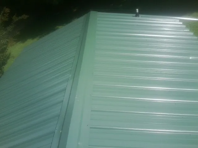 New green metal panels meeting at the ridge of a roof — Flat Roof Repair work by our crew in Kirkland